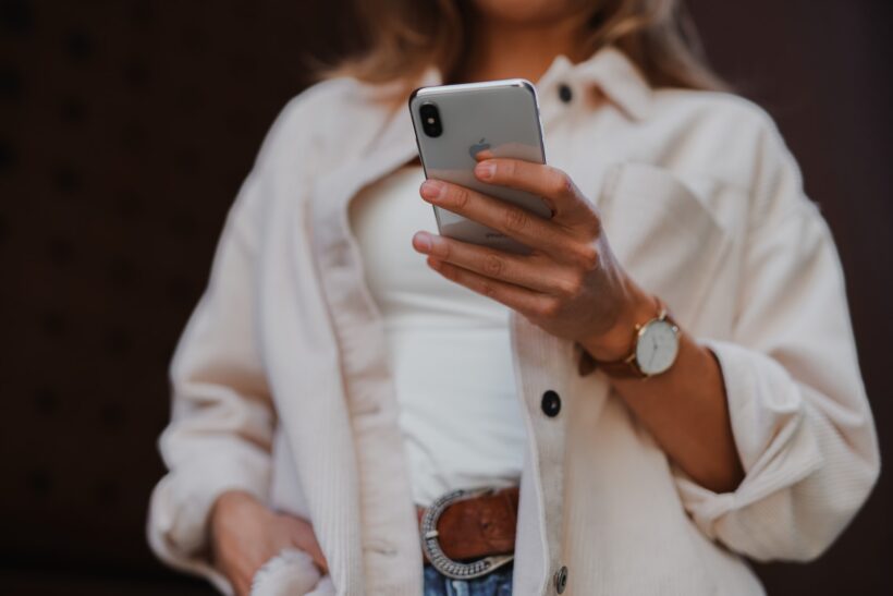 woman in white coat holding silver iphone 6